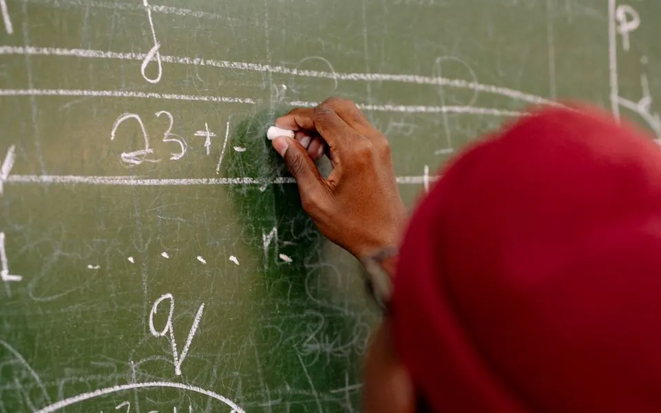 A learner at a blackboard, seen from behind.