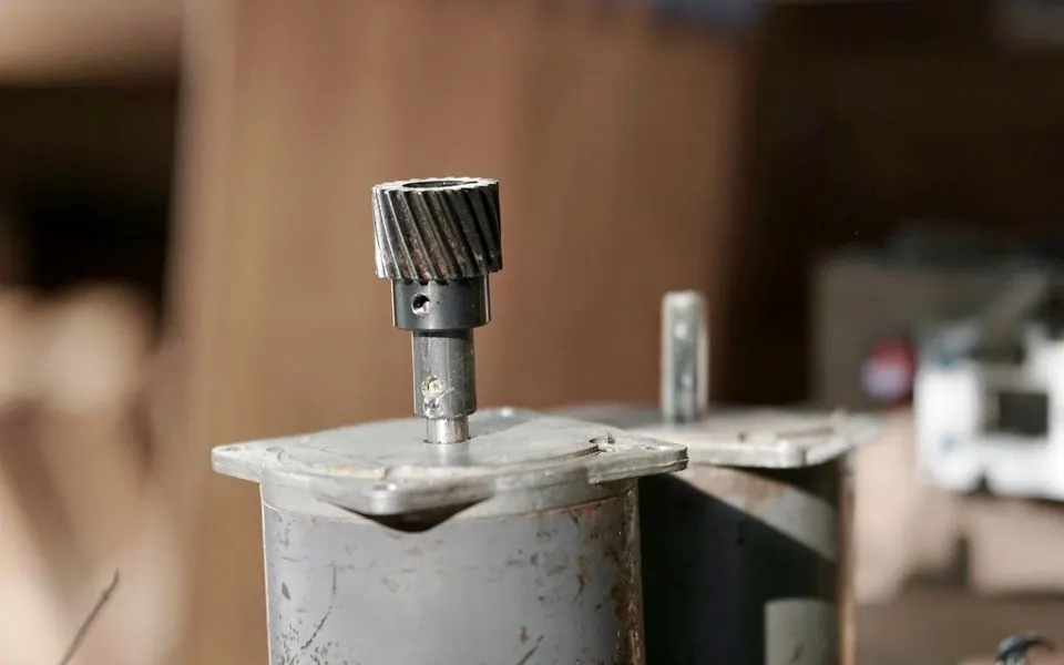 A cut gear standing on a workbench beside its fixture.