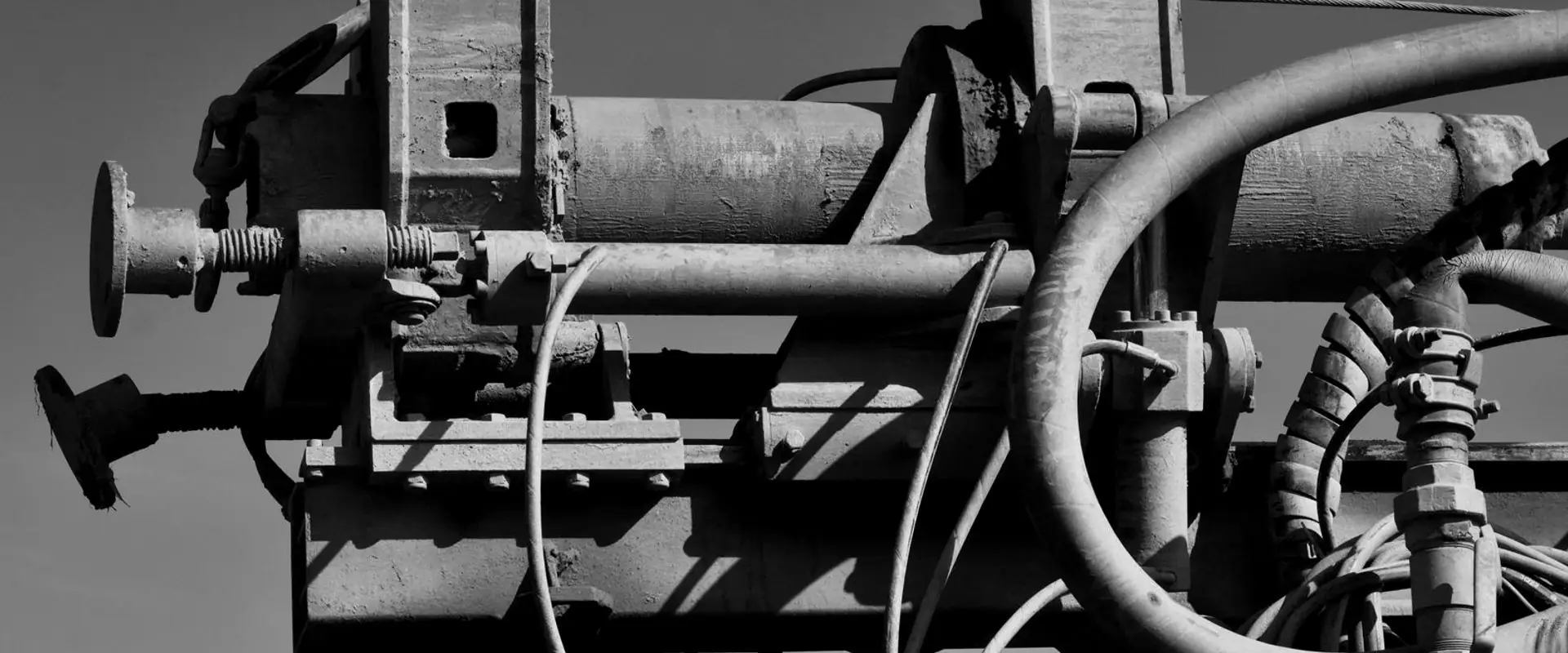 The head of a piece of industrial plant against open sky, its rams, hoses and cabling in close detail.